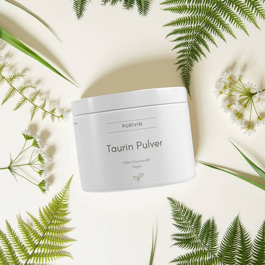 Purivin Taurin Pulver – veganes, reines Taurinpulver ohne Zusatzstoffe, fotografiert auf hellem Hintergrund mit Farnen und Blüten.